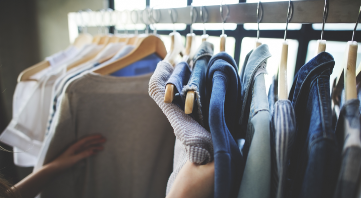 apparel stocks: a person looking at several pieces of clothing hanging on a rack