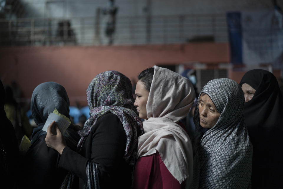 People wait in queues to receive cash at a money distribution organized by the World Food Program (WFP) in Kabul, Afghanistan, Wednesday, Nov. 3, 2021. Afghanistan's economy is fast approaching the brink and is faced with harrowing predictions of growing poverty and hunger. (AP Photo/Bram Janssen)