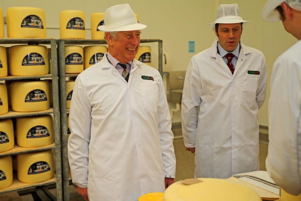 King Charles visits a cheese factory wearing a white coat and hat