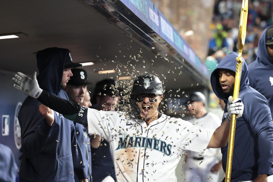 Seattle Mariners' Josh Rojas gets sunflower seeds tossed at him in the dugout after his home run off Texas Rangers pitcher Jonathan Hernández during the seventh inning of a baseball game Saturday, June 15, 2024, in Seattle. (AP Photo/Jason Redmond)