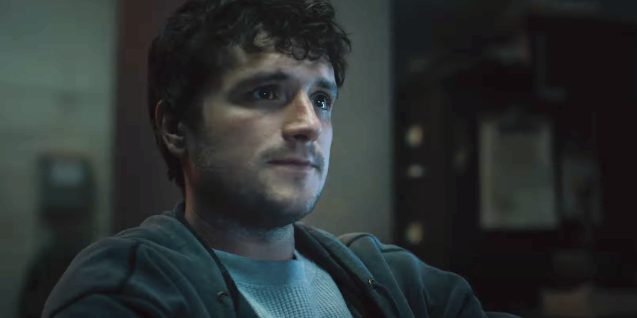 josh hutcherson in five nights at freddy's, a young man with dark hair wears a tshirt and jacket indoors, sitting looking off into the distance