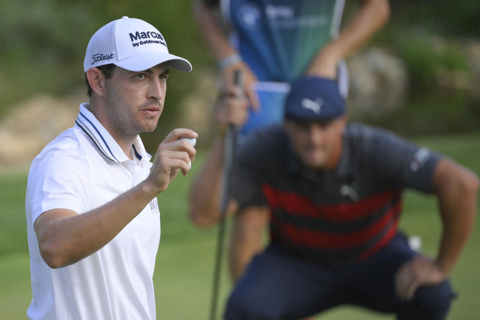 Patrick Cantlay, left, reacts after sinking his putt on the 18th green as Bryson DeChambeau, right, lines up his putt during the final round of the BMW Championship golf tournament, Sunday, Aug. 29, 2021, at Caves Valley Golf Club in Owings Mills, Md. (AP Photo/Nick Wass)