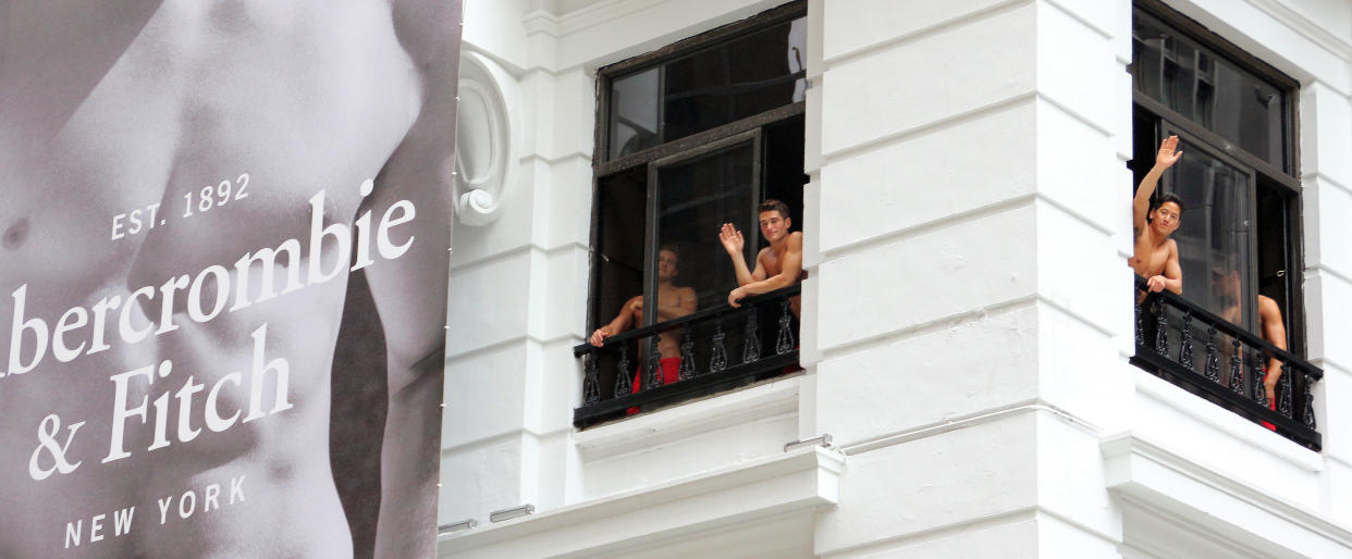 Topless male models wave to a crowd of onlookers from the soon to open Abercrombie & Fitch flagship clothing store in Hong Kong on August 5, 2012. The store is due to be opened for trading on August 11.    AFP PHOTO / LAURENT FIEVET        (Photo credit should read LAURENT FIEVET/AFP/GettyImages)