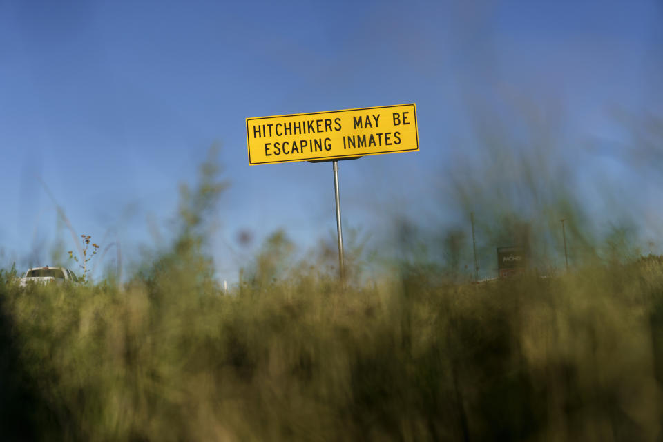 A sign warns passing motorists that hitchhikers may be escaping inmates in Midland, Texas, Monday, Oct. 11, 2021. Centered around the boomtowns of Midland and Odessa, the Permian Basin is now the top oil and gas producing region in the United States, which in turn is the world’s No. 1 producer. (AP Photo/David Goldman)