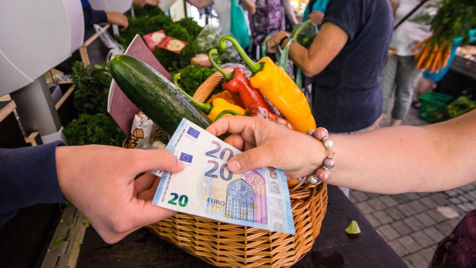 Eine Frau bezahlt an einem Gemüsestand auf dem Wochenmarkt mit Bargeld ihren Einkauf. Das mit Bargeld gezahlt wird kommt in Deutschland immer seltener vor. Foto: Christoph Schmidt