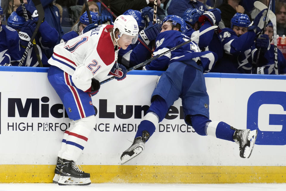 Montreal Canadiens defenseman Kaiden Guhle (21) checks Tampa Bay Lightning left wing Brandon Hagel (38) into the boards during the second period of an NHL hockey game Wednesday, Dec. 28, 2022, in Tampa, Fla. (AP Photo/Chris O'Meara)