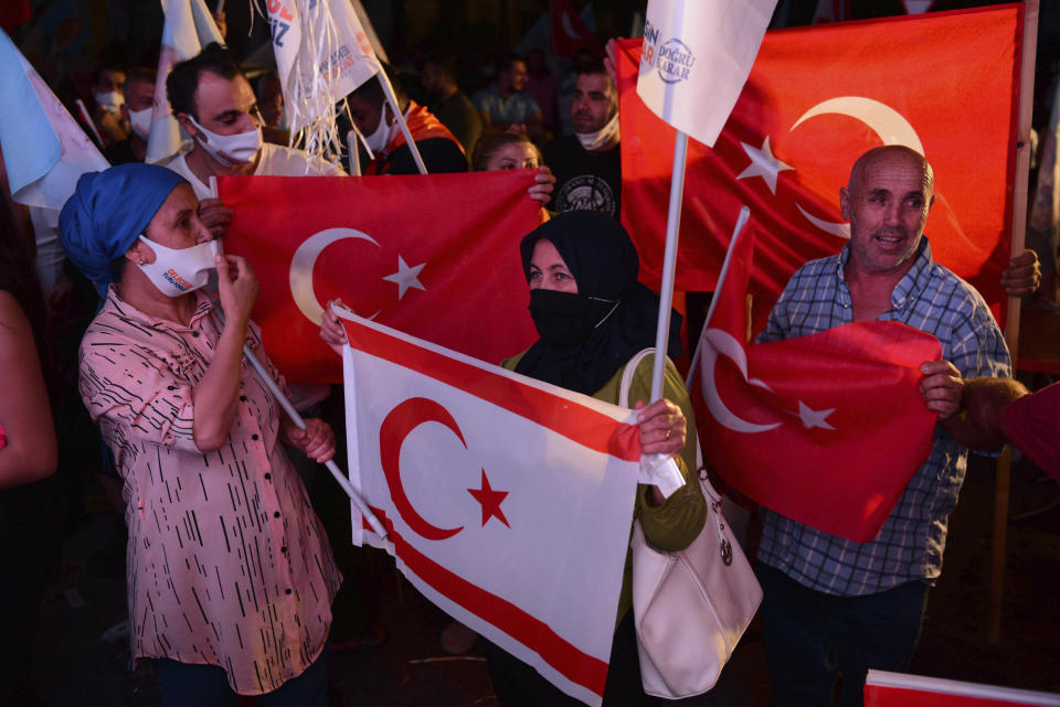 Supporters of a newly elected Turkish Cypriot leader Ersin Tatar hold Turkish and Turkish Cypriot flags and celebrate after winning the Turkish Cypriots election, in the Turkish occupied area in the north part of the divided capital Nicosia, Cyprus, Sunday, Oct. 18, 2020. Ersin Tatar, a hardliner who favors even closer ties with Turkey and a tougher stance with rival Greek Cypriots in peace talks has defeated the leftist incumbent in the Turkish Cypriot leadership runoff. (AP Photo/Nedim Enginsoy)