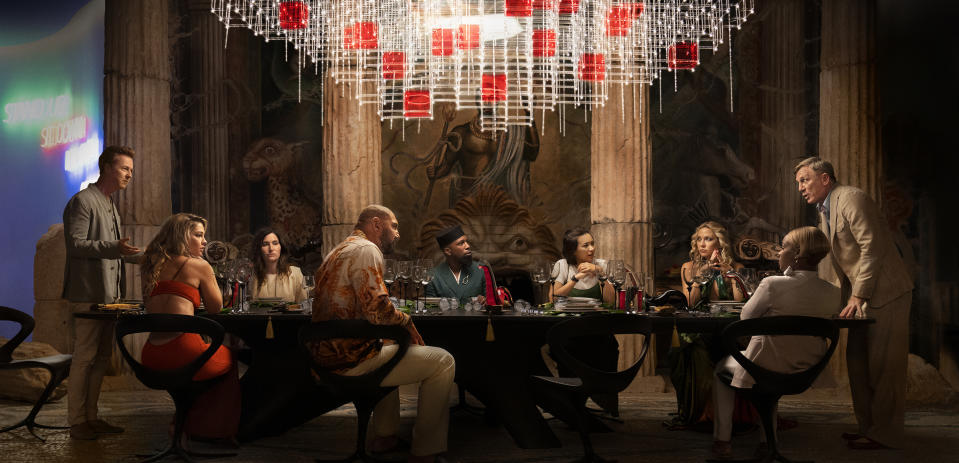 This image released by Netflix shows, from left, Edward Norton, Madelyn Cline, Kathryn Hahn, Dave Bautista, Leslie Odom Jr., Jessica Henwick, Kate Hudson, Janelle Monae, and Daniel Craig in a scene from "Glass Onion: A Knives Out Mystery." (Netflix via AP)