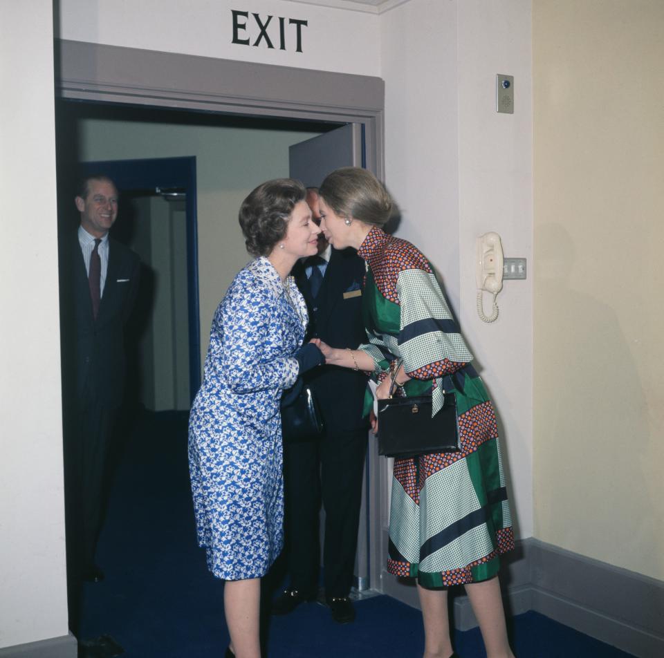 Queen Elizabeth II and Princess Anne greet each other with a kiss in 1970.