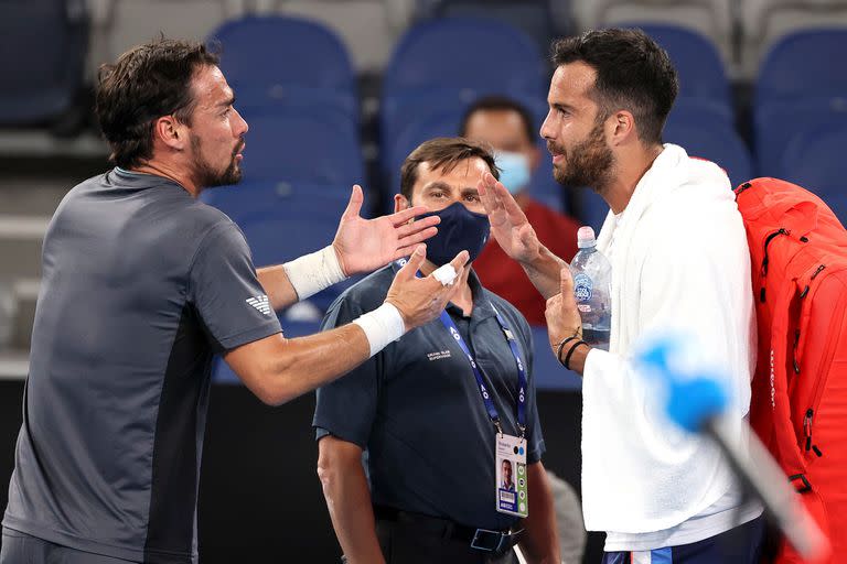 El jugador italiano Salvatore Caruso (derecha) y Fabio Fognini discuten después de su partido individual masculino en el cuarto día del torneo de tenis Abierto de Australia en Melbourne el 11 de febrero de 2021.