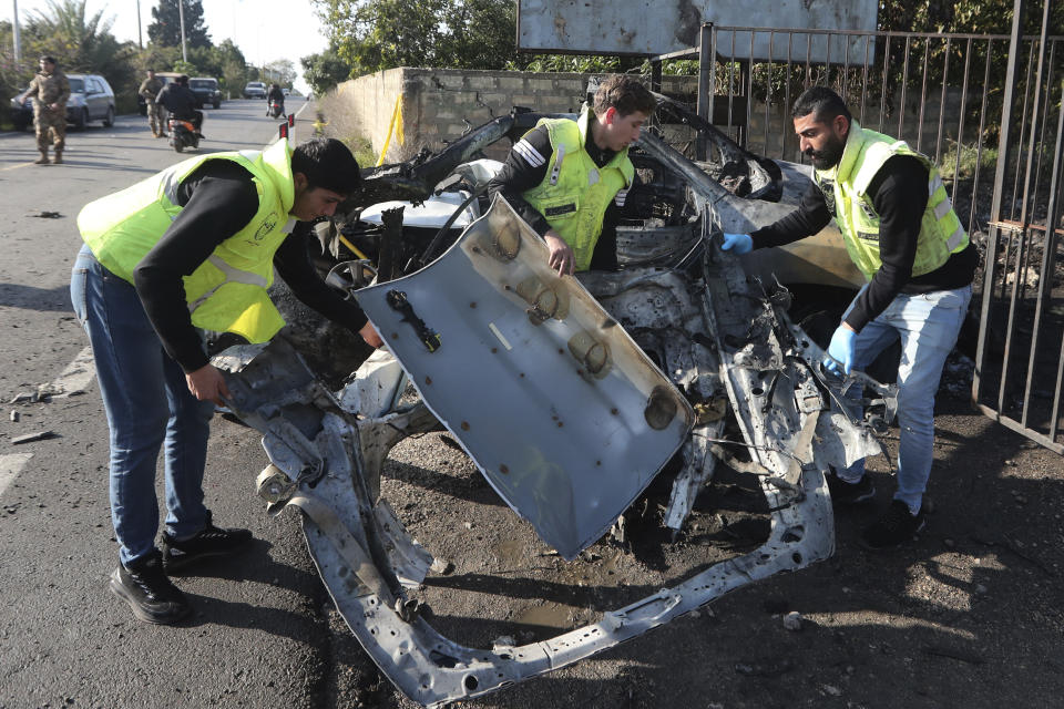 Civil defense workers remove parts of a destroyed car in the southern town of Bazouriyeh, Lebanon, Saturday, Jan. 20, 2024. An Israeli drone strike on the car near the Lebanese southern port city of Tyre killed two people, the state-run National News Agency reported. (AP Photo/Mohammad Zaatari)