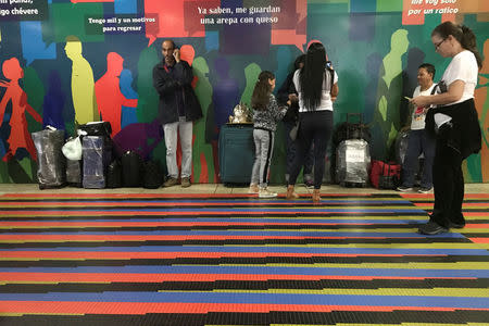 People wait by a counter of Copa Airlines, at the Simon Bolivar airport in Caracas, Venezuela April 6, 2018. REUTERS/Marco Bello