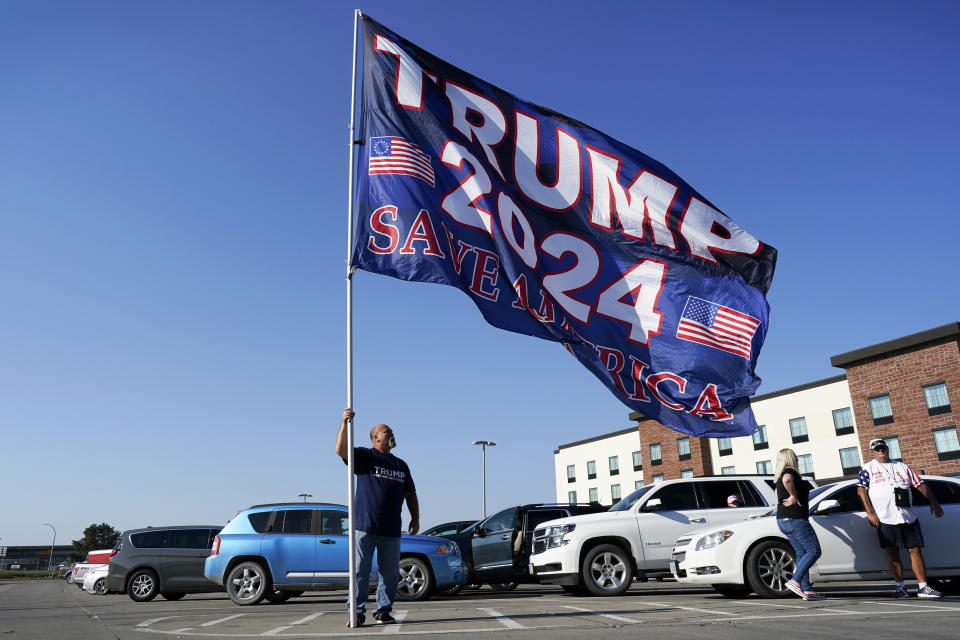 A supporter of former President Donald Trump holds a flag before a rally, Sunday, Oct. 1, 2023, in Ottumwa, Iowa. (AP Photo/Charlie Neibergall)