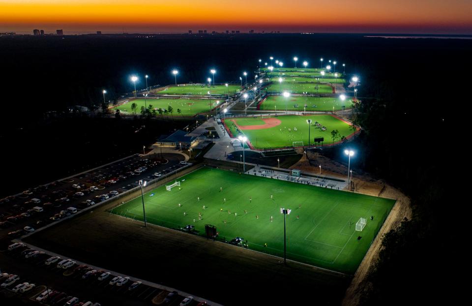 The PCB Sport Complex shines under night lights at sunset.