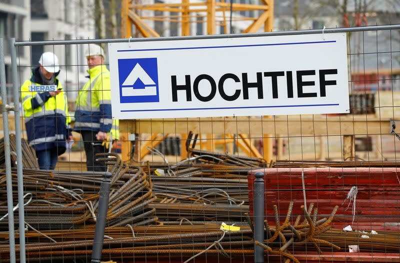 Workers of German construction company Hochtief stand next to the company's logo in Essen