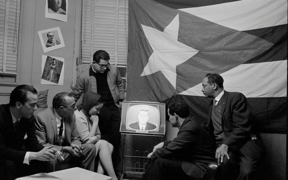 A group of Cuban refugees in Manhattan watch John F. Kennedy, the former US president, delivering a speech on television - Bettmann