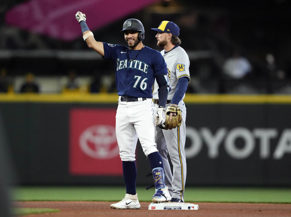 Seattle Mariners' Jose Caballero celebrates a double, his first major league hit, during the third inning against the Milwaukee Brewers as second baseman Brice Turang looks on in a baseball game Wednesday, April 19, 2023, in Seattle. (AP Photo/Lindsey Wasson)