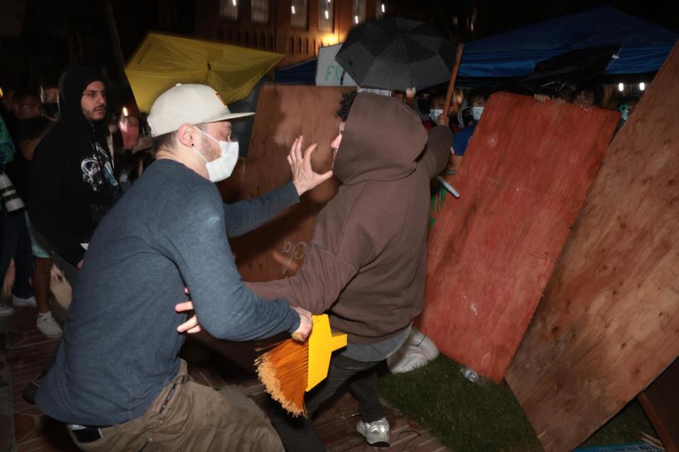 Two people fight near a plywood barrier