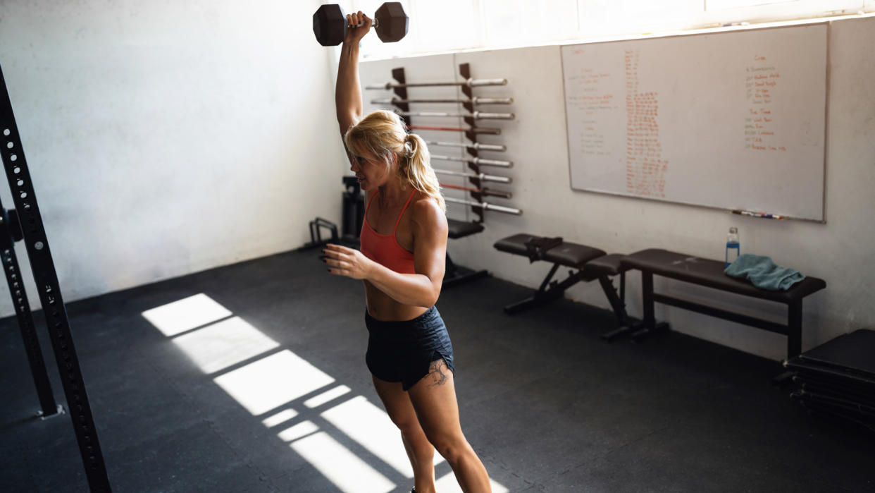  Woman doing overhead dumbbell marches. 