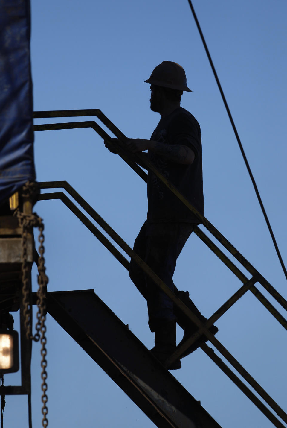 FILE - In this Feb. 21, 2012, file photo, an oil field worker climbs stairs on a drilling rig near Medicine Lodge, Kan., where horizontal drilling and a technique known as hydraulic fracturing, or “fracking,” is used to coax out oil and gas. Illinois legislation is advancing that would regulate decades-old but debated technology used to reach previously inaccessible natural gas reserves deep underground. The Illinois state Senate on Thursday, April 26, 2012, unanimously sent to the House a bill addressing hydraulic fracturing, or fracking. That technology involves using mixtures of water, sand and chemicals to free below-ground energy reserves. (AP Photo/Orlin Wagner, File)