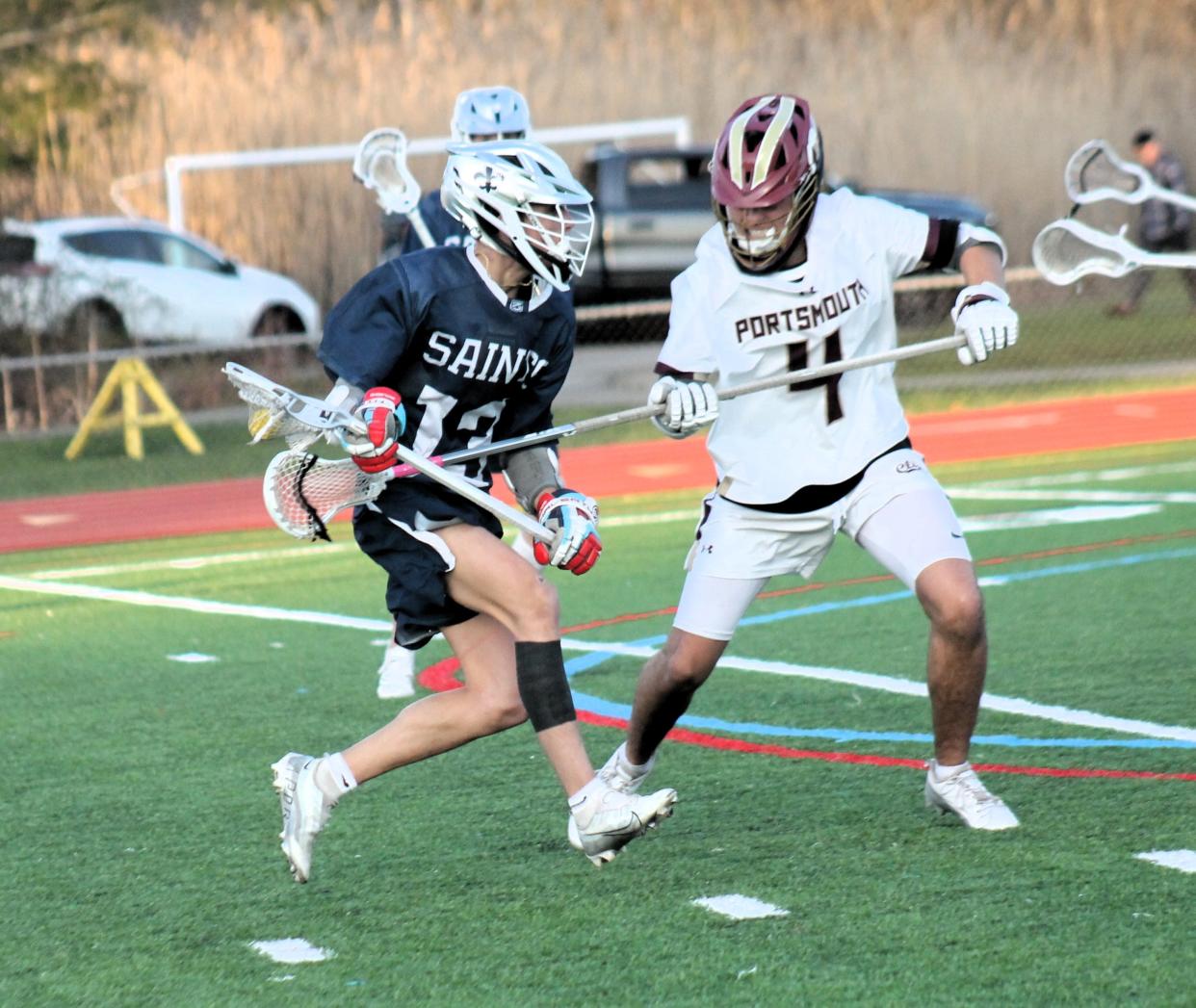 STA's Finley DeTolla, left, finds some resistance in Portsmouth defender Masi Shone during Monday night's Division II boys lacrosse game in Portsmouth. The Clippers held off the rival Saints, 10-9 and remained undefeated on the season.