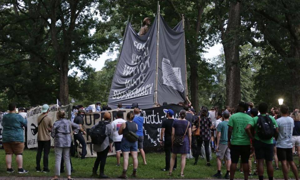 Banners are used to cover the statue as people gather during a rally to remove it.