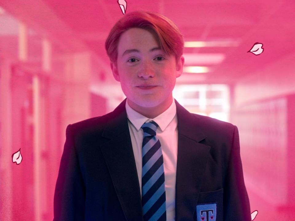 A teen boy smiling in a glowing pink hallway.