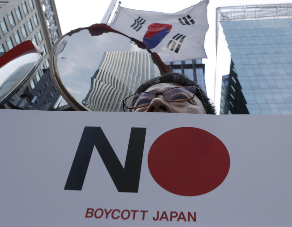 A member of the Confederation of Korean Government Employees' Unions holds a banner near the Japanese embassy in Seoul, South Korea, Tuesday, Aug. 6, 2019. South Korea's president on Monday described the country's escalating trade war with Japan as a wake-up call to revamp its economy and issued a nationalistic call for economic cooperation with North Korea, which he said would allow the Koreas to erase Japan's economic superiority in "one burst." (AP Photo/Lee Jin-man)