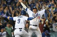 Oct 16, 2018; Los Angeles, CA, USA; Los Angeles Dodgers shortstop Manny Machado (8) celebrates with catcher Yasmani Grandal (9) after scoring on an RBI single by center fielder Cody Bellinger (not pictured) defeat the Milwaukee Brewers in the thirteenth inning in game four of the 2018 NLCS playoff baseball series at Dodger Stadium. Mandatory Credit: Richard Mackson-USA TODAY Sports