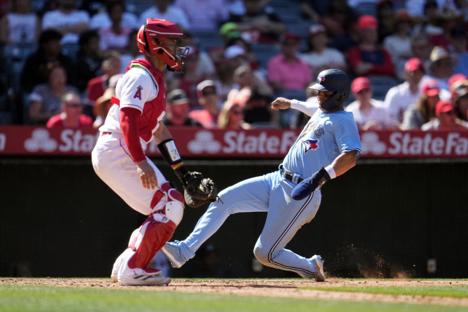 Toronto Blue Jays' Whit Merrifield, right, scores past Los Angeles Angels catcher Logan O'Hoppe on a single by Kevin Kiermaier during the seventh inning of a baseball game, Sunday, April 9, 2023, in Anaheim, Calif. (AP Photo/Marcio Jose Sanchez)