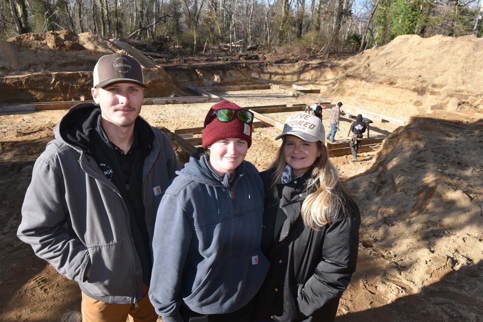 Casey Furnas, left, with LaBarge Homes and Jess Kimball and Sarah Kimball at the site at 82 Monument Road in Orleans where they are building new homes at what they consider a reasonable cost, allowing them to stay on the Cape. The group bought and demolished a dilapidated house to clear the way for their new homes. Steve Heaslip/Cape Cod Times
