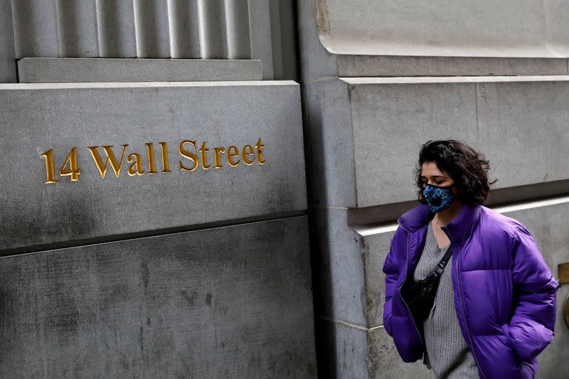 FILE PHOTO: A person wearing a face mask walks along Wall Street after further cases of coronavirus were confirmed in New York City, New York