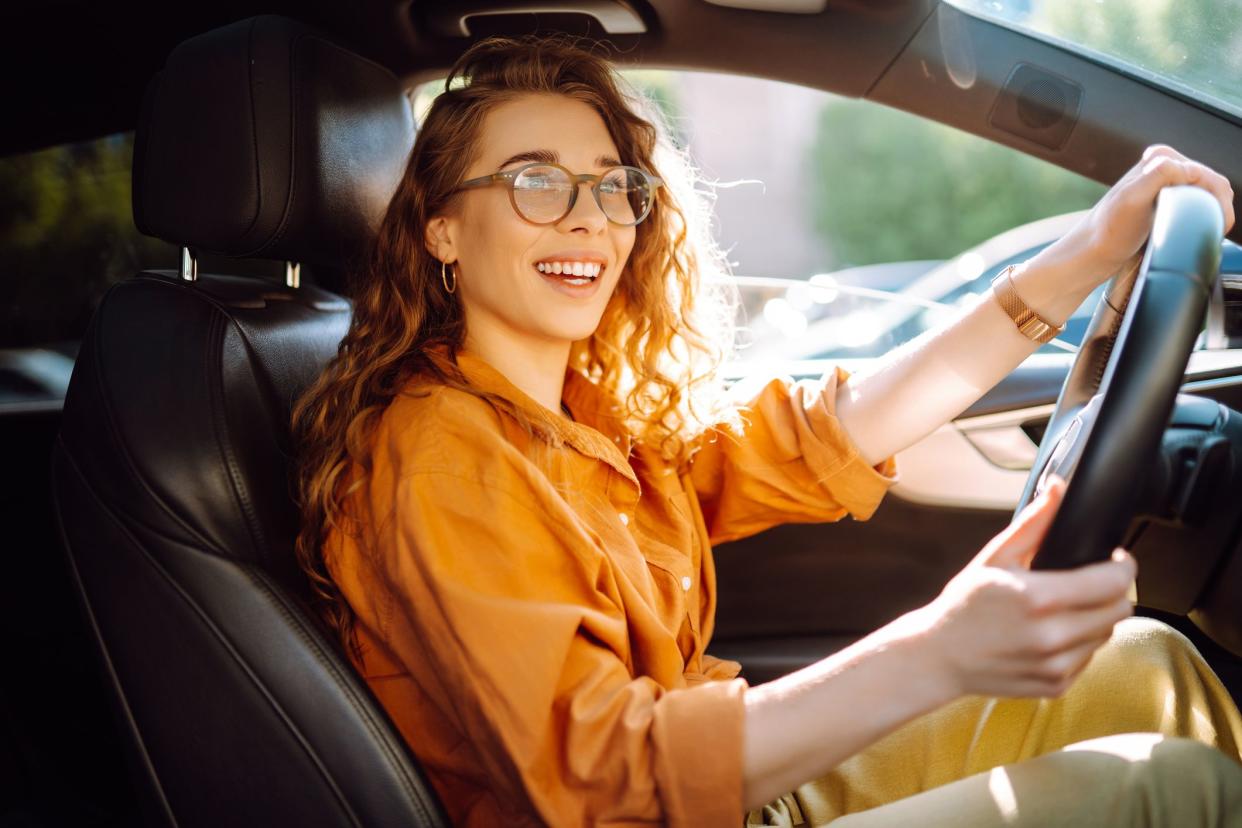 Stylish woman driving a car. The traveler is the driver. Automobile travel. Sharing a car. Lifestyle concept.