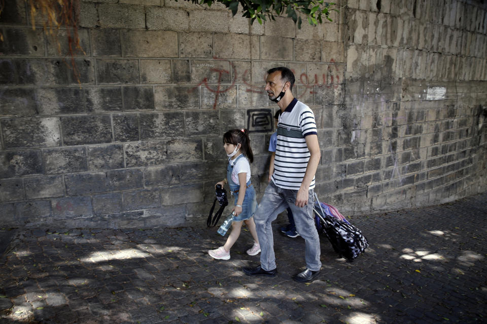 A man walks with his children at the end of their school day in Beirut, Lebanon, Wednesday, Sept. 29, 2021. Lebanese students are returning to schools, many for the first time since late 2019, but the country's crippling economic crisis is threatening to derail the first in-class academic year after the pandemic. Public school teachers are on strike, demanding their pay be adjusted to make up for the collapse of the national currency, and a severe fuel shortage threatens to keep classrooms dark. (AP Photo/Bilal Hussein)