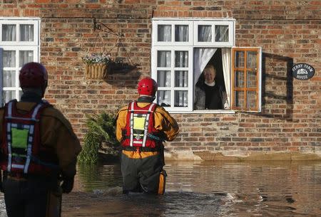 Members of the emergency services approach a woman waiting to be rescued on a flooded street in Naburn, northern England, December 27, 2015. REUTERS/Phil Noble