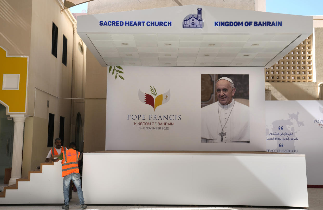 Workers adjust stairs on a podium next to a portrait of Pope Francis during preparations for the papal visit at the Sacred Heart Church in Manama, Bahrain, Wednesday, Nov. 2, 2022. Pope Francis is making the November 3-6 visit to participate in a government-sponsored conference on East-West dialogue and to minister to Bahrain's tiny Catholic community, part of his effort to pursue dialogue with the Muslim world. (AP Photo/Hussein Malla)