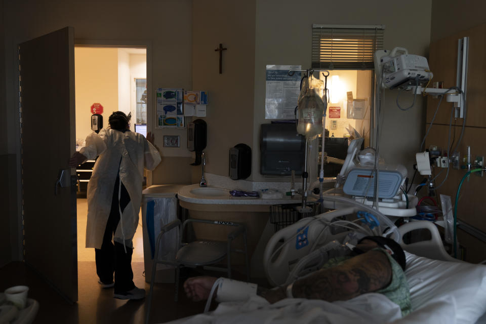 Registered nurse Emily Yu asks her colleague to bring a medical kit while treating Paul Altamirano, 50, foreground, in a COVID-19 unit at Providence Holy Cross Medical Center in Los Angeles, Tuesday, Dec. 14, 2021. "This is nowhere to be. I didn't take it. Now I'm regretting it," said the unvaccinated patient. "I hope I make it. I just gotta be strong." (AP Photo/Jae C. Hong)