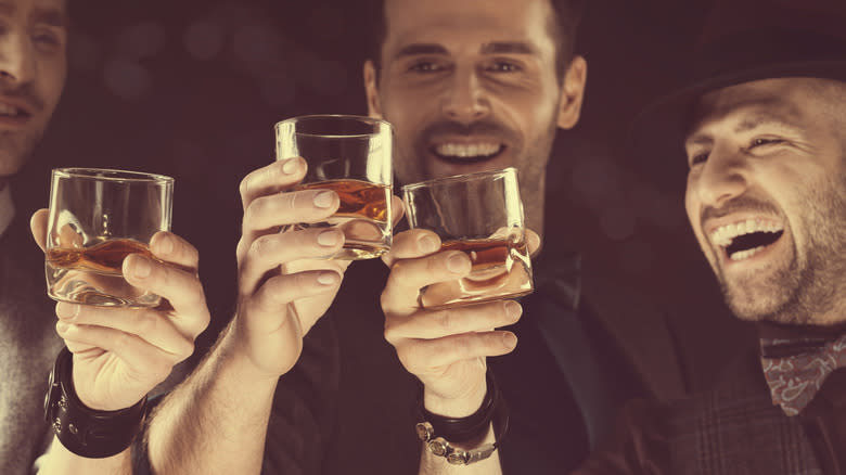 three men toasting bourbon glasses