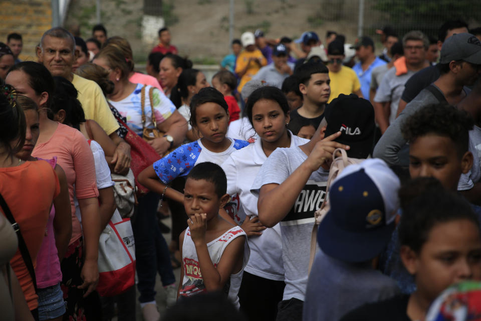Migrants from countries including Honduras, Cuba, Venezuela, and Nicaragua, line up to receive a meal donated by volunteers from the U.S., at the foot of the bridge that crosses to Brownsville, Texas, in downtown Matamoros, Tamaulipas state, Mexico, Wednesday, June 26, 2019. Hundreds of migrants, some of whom have been in line for months, are awaiting their turn to request asylum in the U.S. (AP Photo/Rebecca Blackwell)