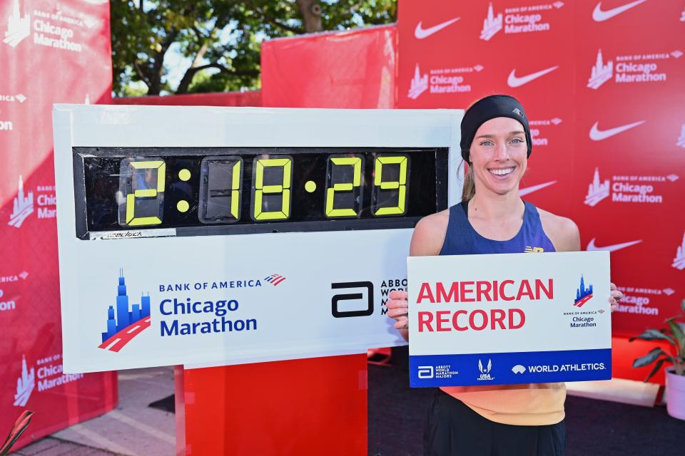 Emily Sisson poses next to her time after setting an American women's marathon record at the 2022 Chicago Marathon.