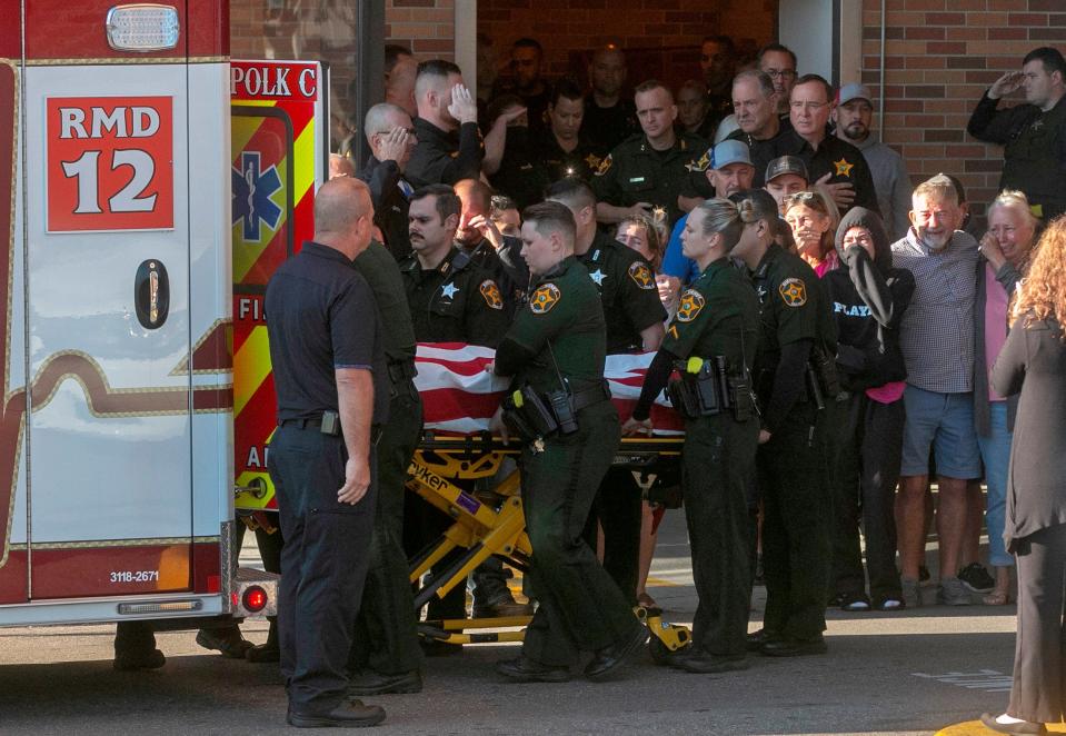 Law enforcement officials place the body of Polk County Sheriff's Deputy Blane Lane, 21, into an ambulance at Lakeland Regional Health Medical Center on Tuesday to be transported to the medical examiner's office. Lane was killed early Tuesday morning while serving a warrant in Polk City. October 4, 2022.