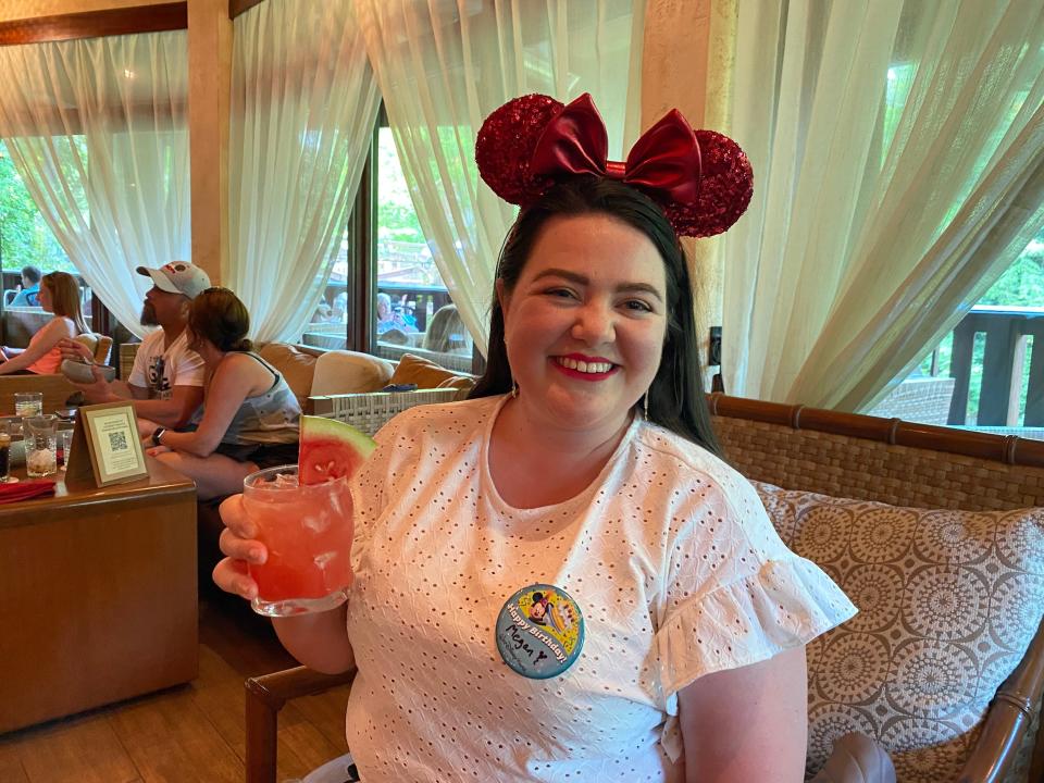 The writer wears red mouse ears and holds a cocktail