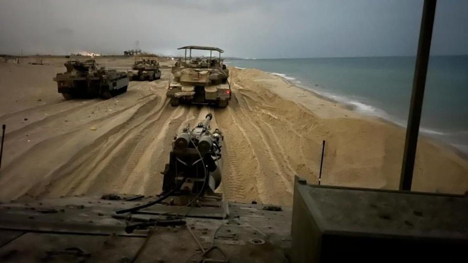 military vehicles driving on a sandy beach