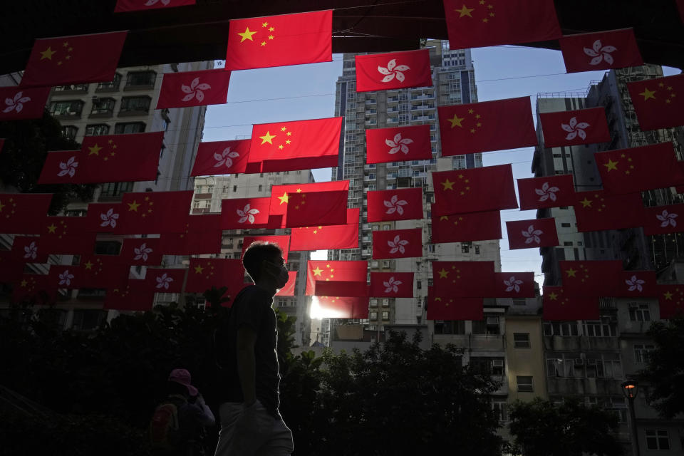 FILE - A man walks past Chinese and Hong Kong flags to celebrate the 25th anniversary of Hong Kong handover to China, in Hong Kong, Friday, June 24, 2022. Hong Kong authorities, citing “security reasons,” have barred more than 10 journalists from covering events and ceremonies this week marking the 25th anniversary of Hong Kong’s return to China, according to the Hong Kong Journalists Association, Tuesday, June 28, 2022. (AP Photo/Kin Cheung, File)