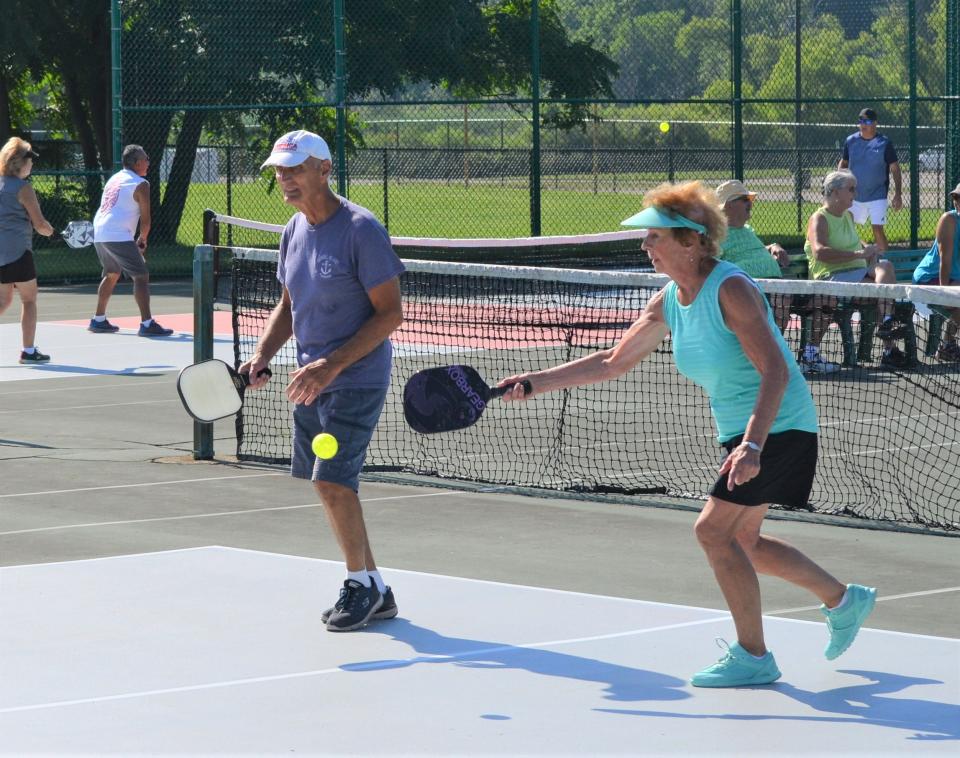 Joyce Ashdon returns a serve as teammate Donald Bouchard looks on during a pickleball match. The Battle Creek Pickleball Club plays several times a week at the refurbished courts at Kellogg Community College.