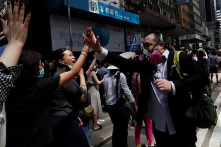 Anti-government office workers wearing masks attend a lunch time protest, after local media reported on an expected ban on face masks under emergency law, at Central, in Hong Kong