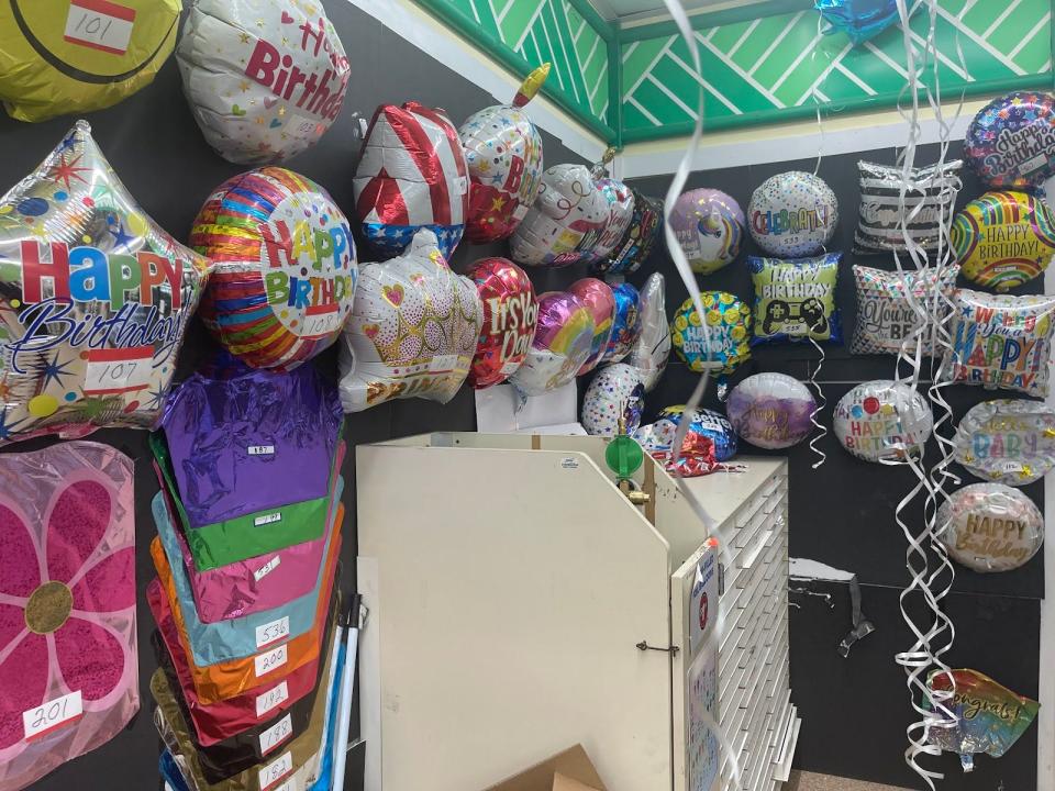 Different helium balloons on display on a wall in a store.