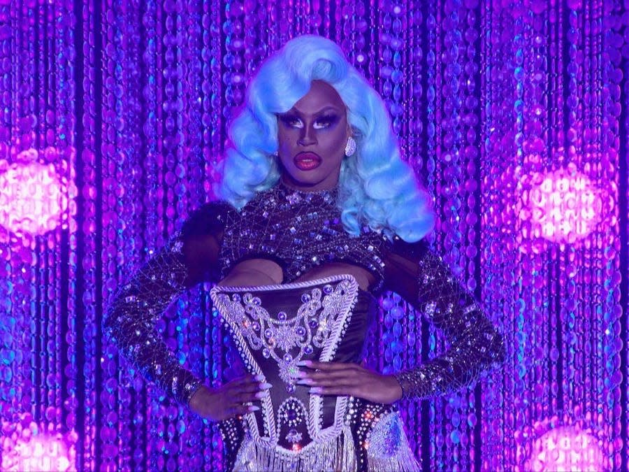 Shea Couleé in blue wig and black ensemble on drag race