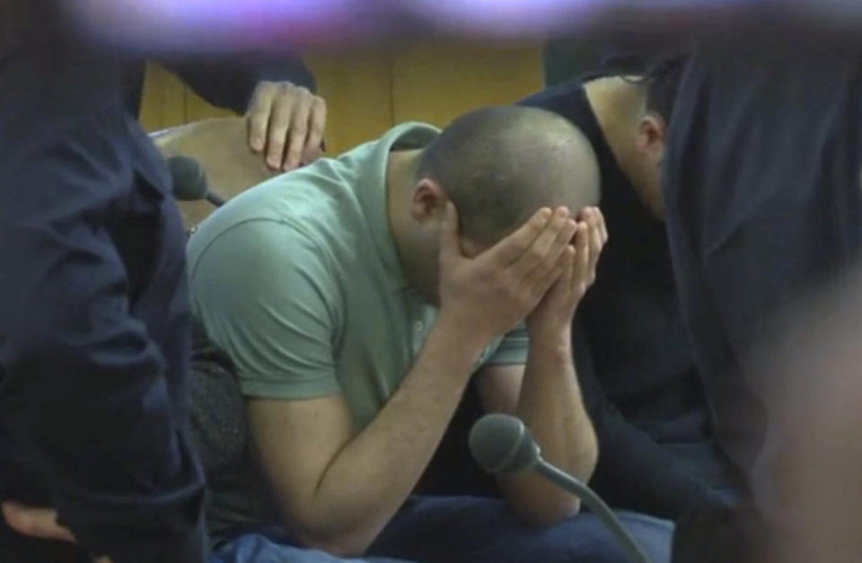 A defendant covers his face at the beginning of his trial on gang-raping a German tourist in Vienna, Austria, Thursday, March 2, 2017. Eight Iraqi nationals have been given jail sentences of between nine and 13 years. (AP Photo/Philipp Jenne)