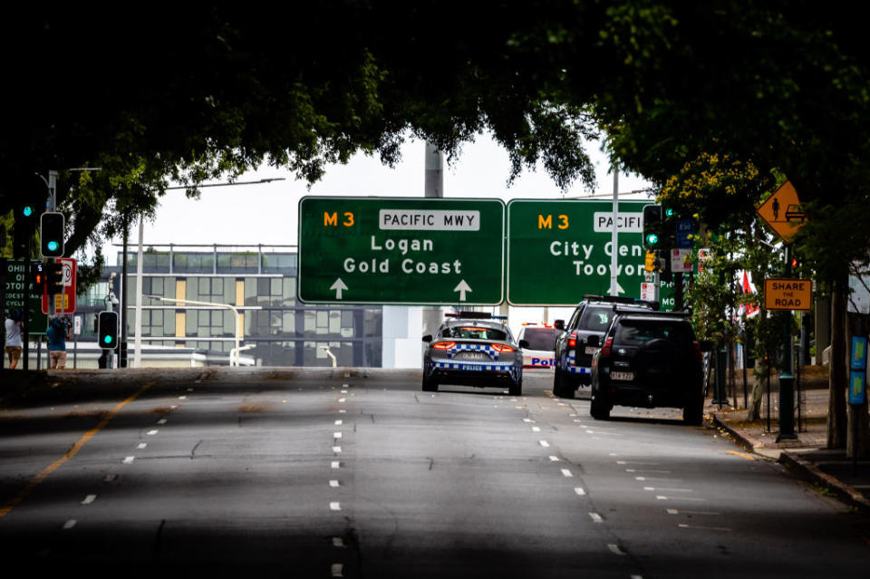 Police vehicles are seen on a deserted street on the first day of a snap lockdown in Brisbane.